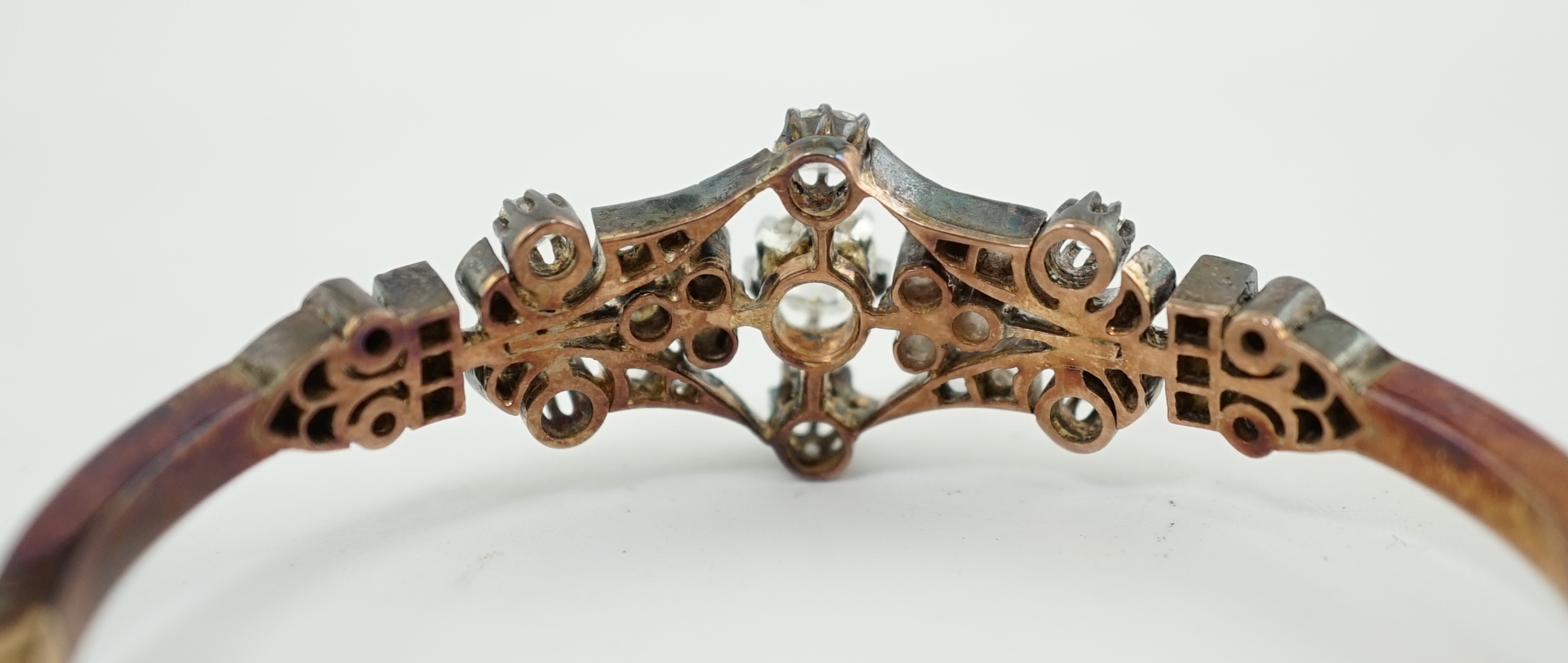 A late 19th/early 20th century French 18ct gold, silver, rose and round cut diamond cluster set hinged bangle